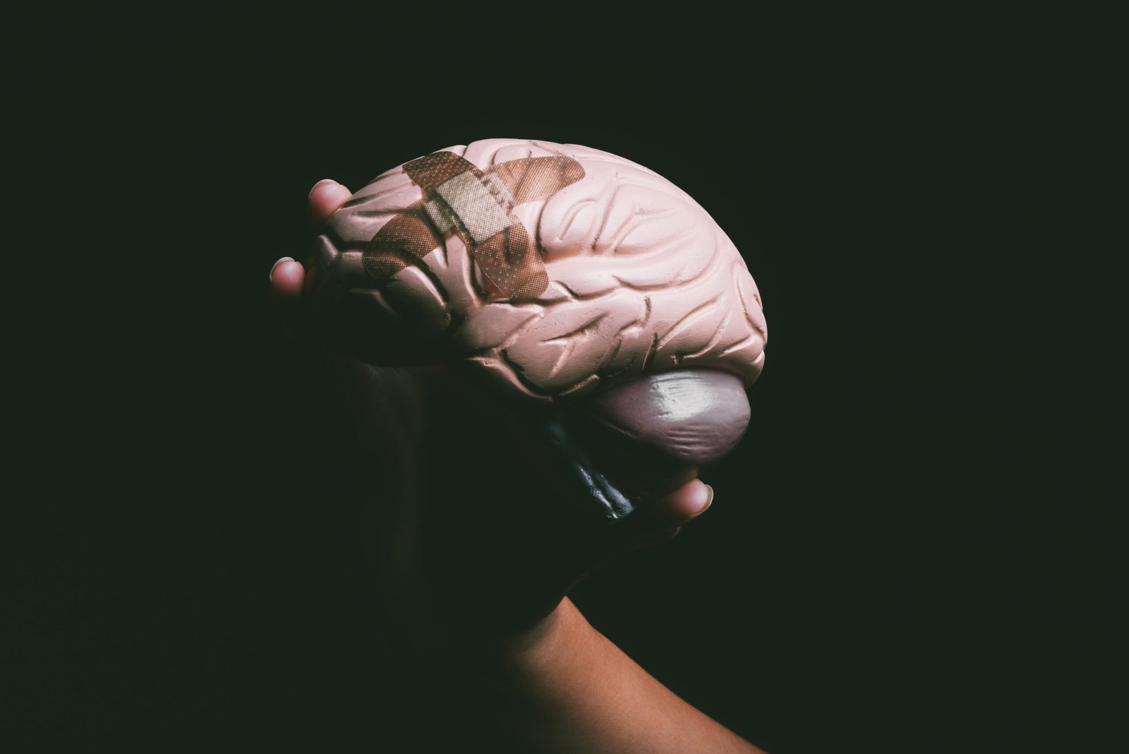 Shot of an unrecognisable person holding a brain with a band aid on it.
