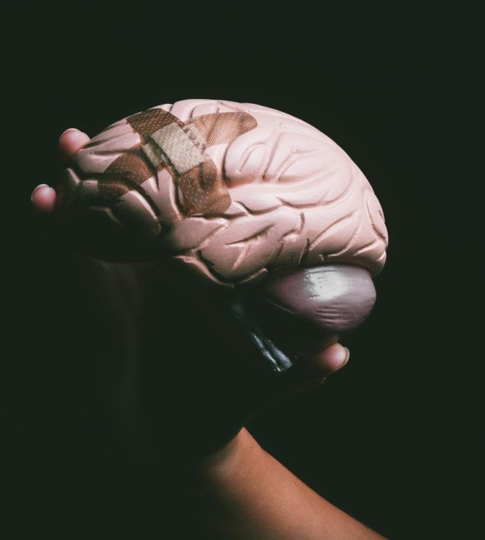 Shot of an unrecognisable person holding a brain with a band aid on it.